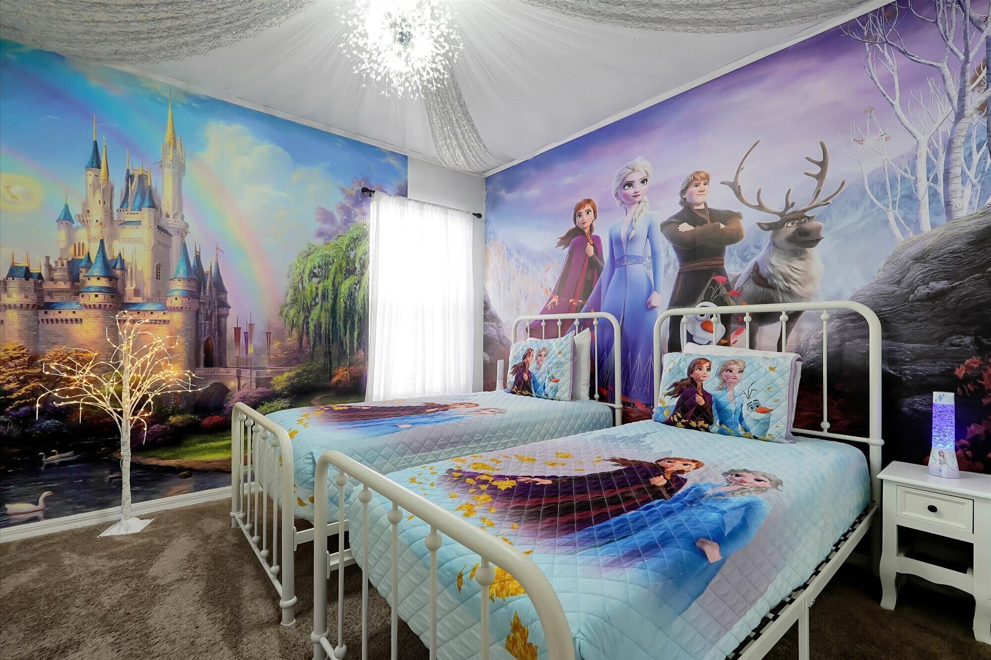 A bedroom with two beds, a mural of a castle and animated characters, and a chandelier.