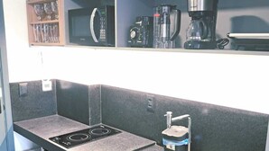 Eine moderne Küche mit eingebautem Herd, einer Spüle und einer Kaffeemaschine auf der Arbeitsfläche.