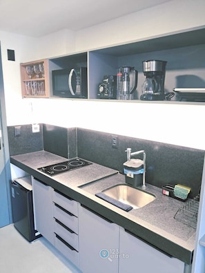 Una cocina moderna con estufa integrada, un lavamanos y una cafetera sobre la encimera.