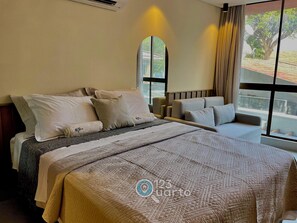 Una habitación de hotel con cama, sofá, ventana grande y aire acondicionado.