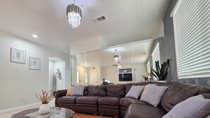 Una sala de estar moderna con un sofá modular, una mesa de centro de vidrio y una araña.