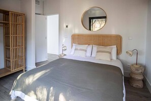 Una camera da letto con un letto grande, un armadio in legno, uno specchio rotondo e una lampada da comodino.