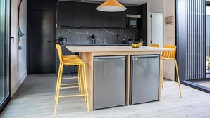 Una cocina moderna con una isla central, electrodomésticos de acero inoxidable y sillas amarillas.
