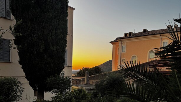 A stone pathway leading through a garden with a building in the background. - la terrazza (Tivoli)