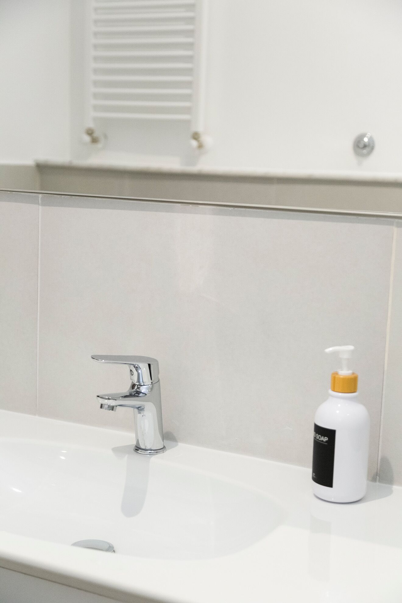 Een badkamer met een wit wastafelmeubel, een chromen kraan en een zeepdispenser.