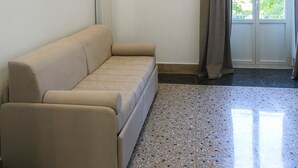 A room with a beige sofa, a radiator, a window with curtains, and a terrazzo floor. - la terrazza (Tivoli)