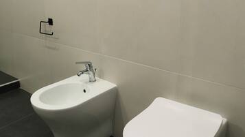 Un baño con bidé, inodoro y perchero para toallas.