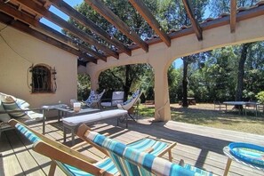 Un espace extérieur abrité doté d’une terrasse en bois, de chaises longues et d’une piscine.