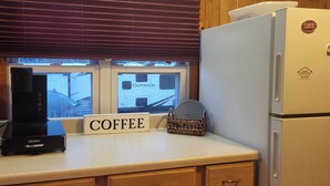 Una cocina con estación de café, estufa, refrigerador y ventana con persianas.