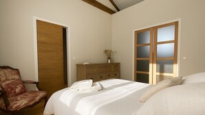 Ein Schlafzimmer mit einem großen Bett, einem hölzernen Schminktisch, einem Sessel und einem Kleiderschrank.