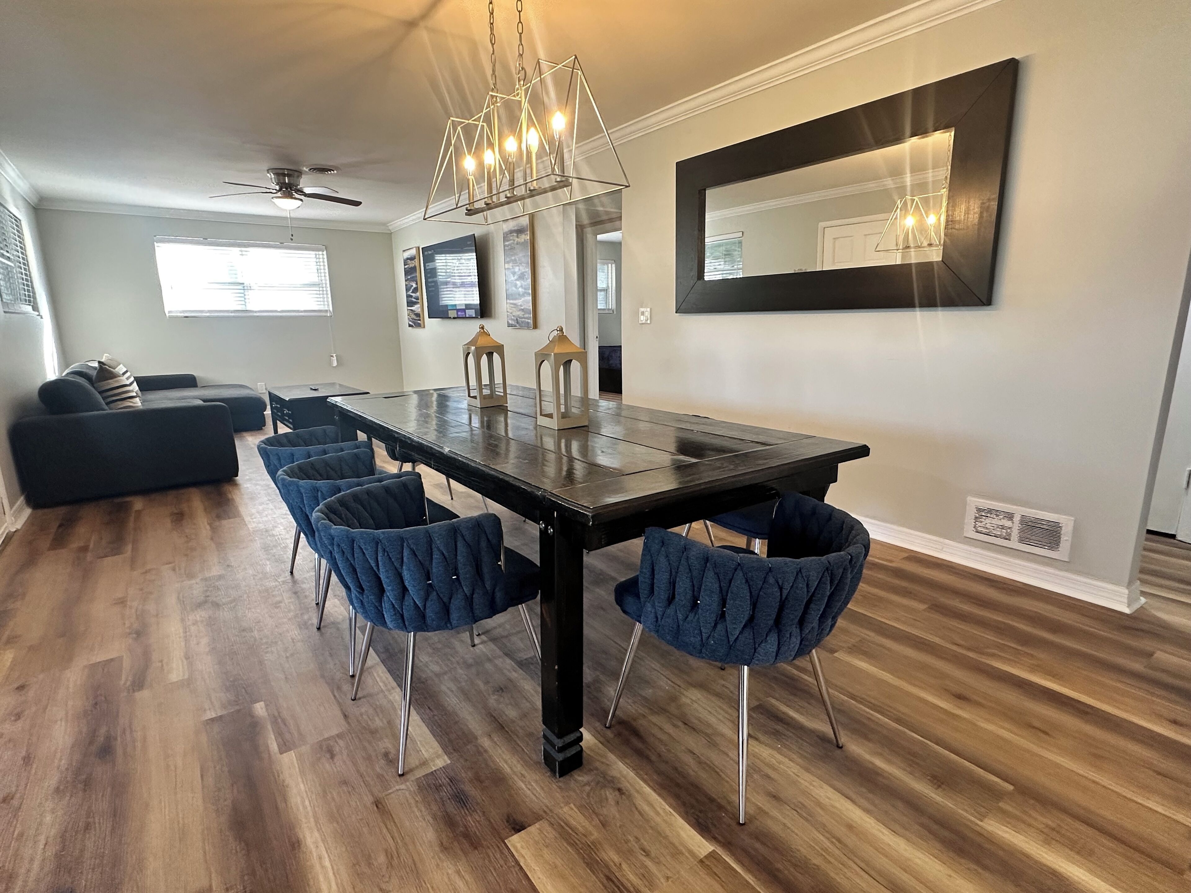A modern dining area with a dark wood table, blue upholstered chairs, and a chandelier.