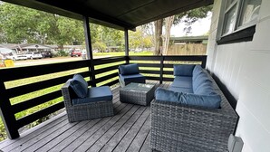 Een overdekte veranda met rieten meubels en uitzicht op de straat.