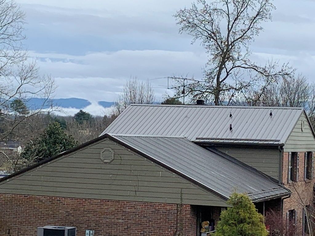 A building with a metal roof and brick walls, a chimney, and a satellite dish.