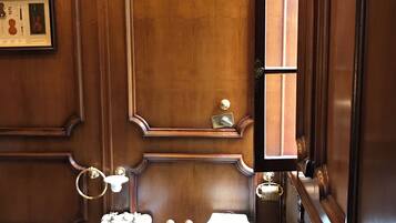 A traditional bathroom with wooden paneling, a pedestal sink, a toilet, and a rug.