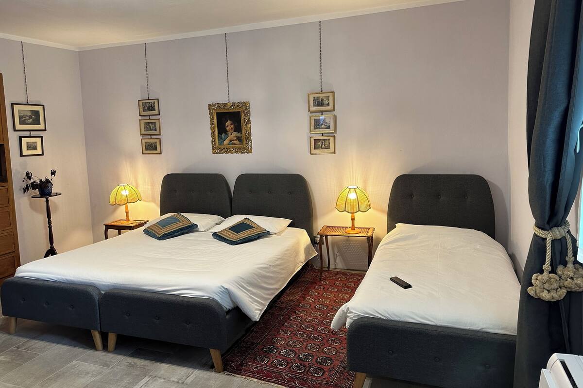 A hotel room with two beds, a red patterned rug, and wall-mounted lamps.