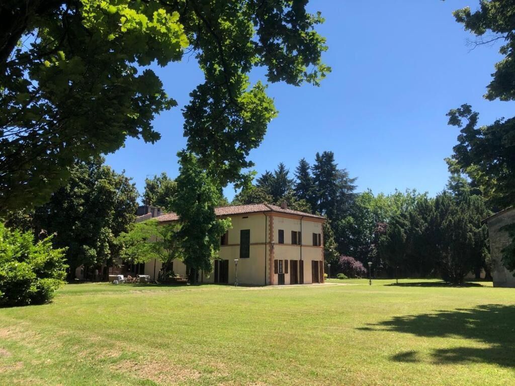 Un edificio a due piani con tetto piatto, circondato da un prato e alberi.