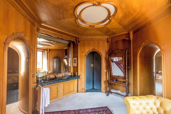 A luxurious bathroom with ornate woodwork, a marble sink, and a large mirror. - Villa Dom (Piacenza)