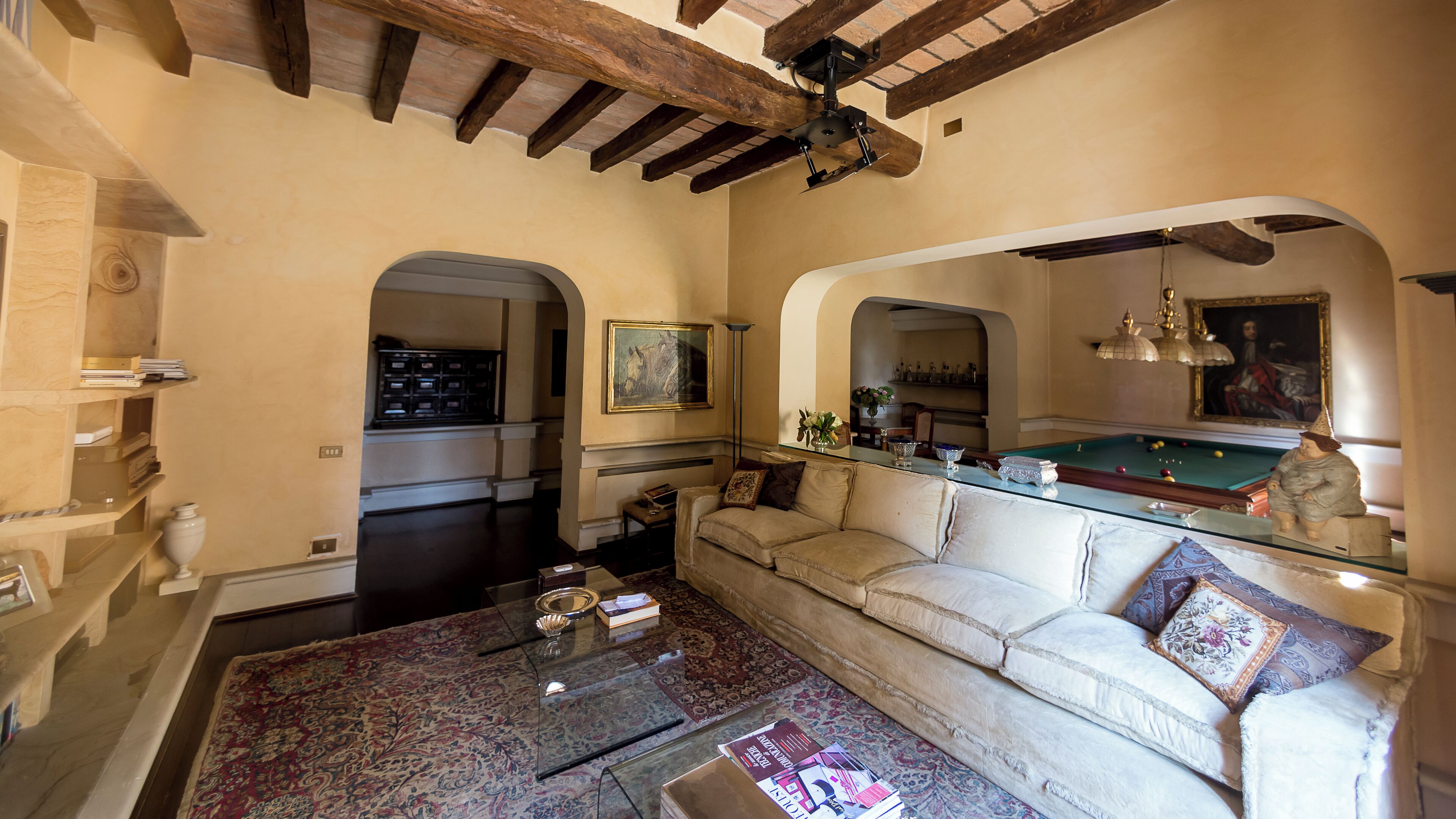 A spacious living room with a billiards table, a sofa, and a coffee table.