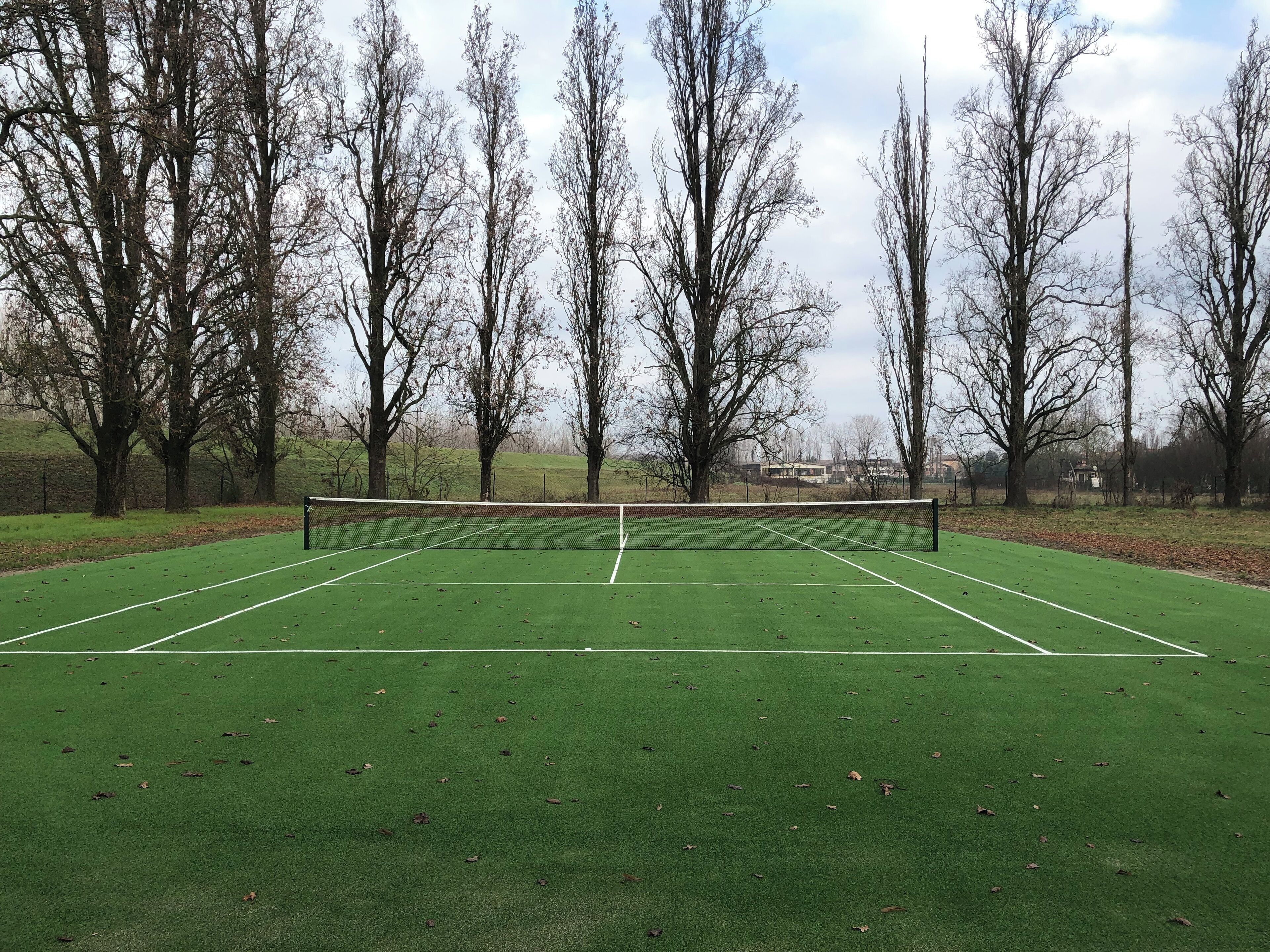 Een tennisbaan omringd door bomen.
