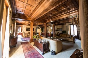 Un salón amplio con techos de madera, un sofá grande, una mesa de centro y una chimenea.