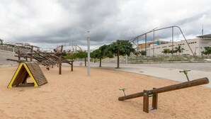 Ein Spielplatz mit Wippe, Klettergerüst und Sandkasten.