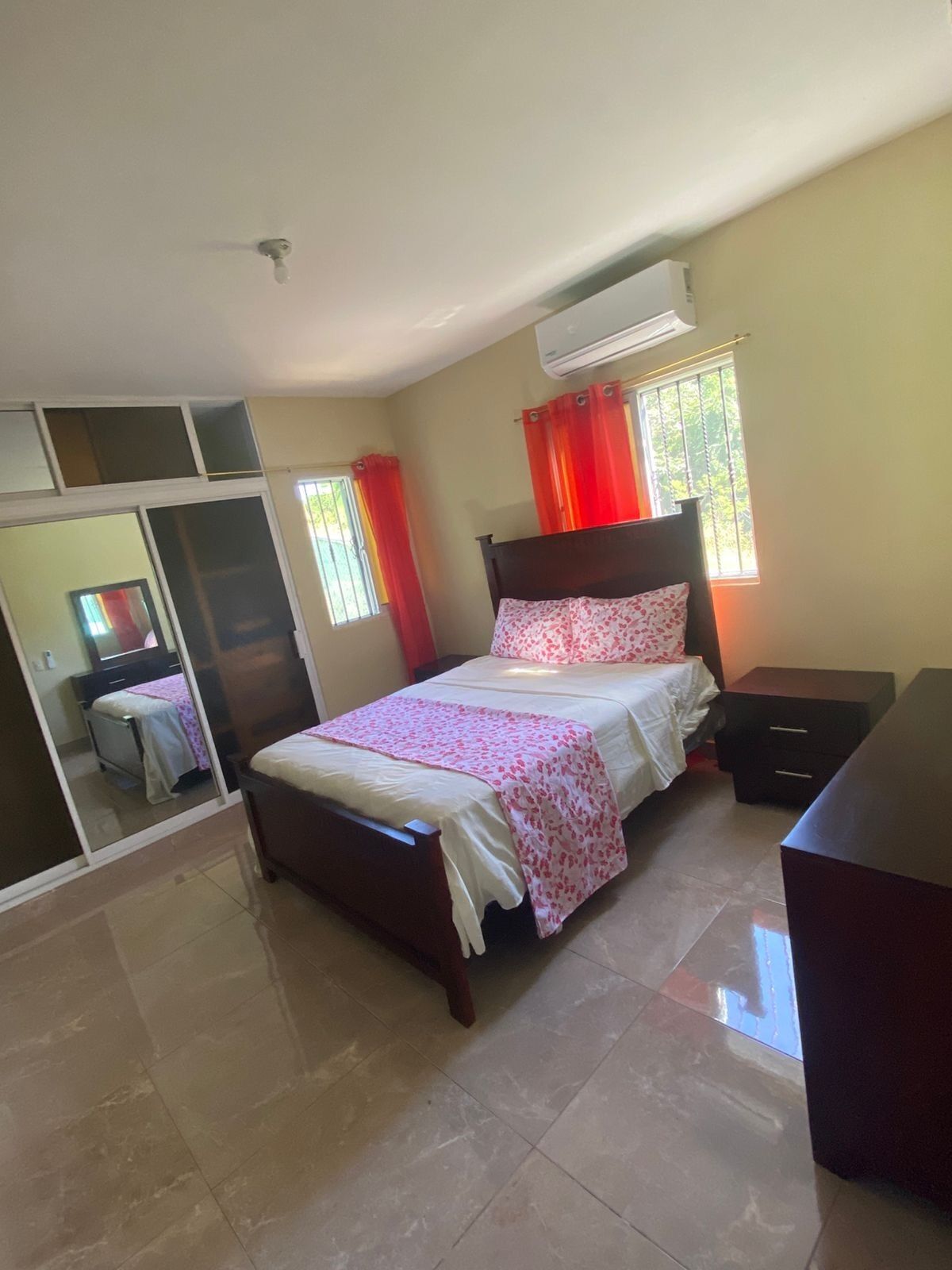 Un dormitorio con cama, cómoda, espejo y aire acondicionado.