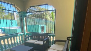 Un balcon agrémenté de meubles en osier, notamment d’un canapé et de deux fauteuils, ainsi qu’une petite table.