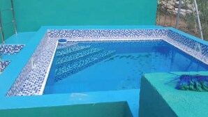 Une piscine aux carreaux de mosaïque bleus et à l’eau d’un bleu limpide.