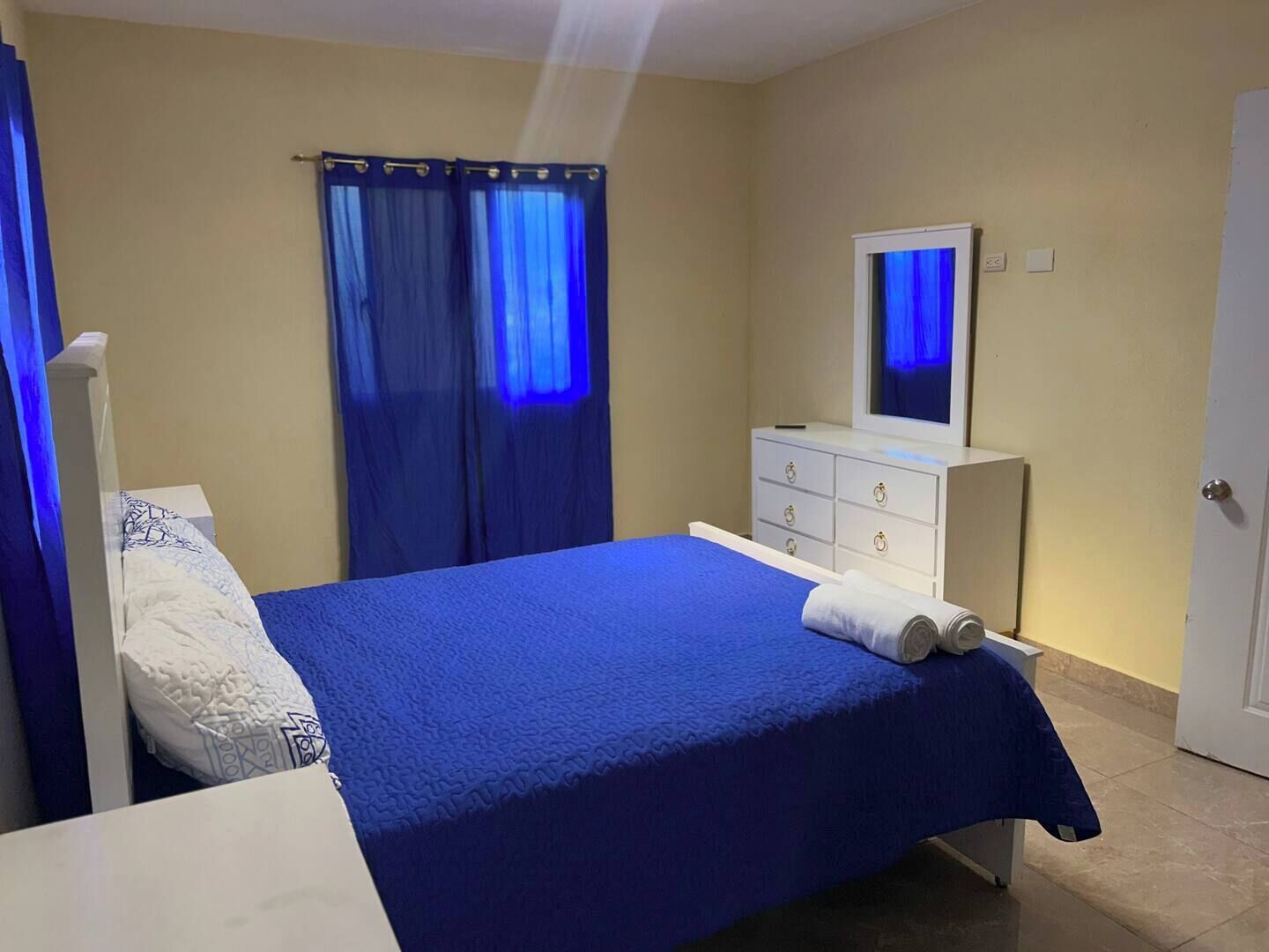 Un dormitorio con cama, cómoda, espejo y puerta.