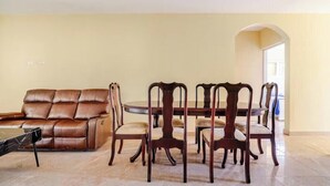 Un coin repas comprenant un canapé en cuir marron, une table ronde et quatre chaises.