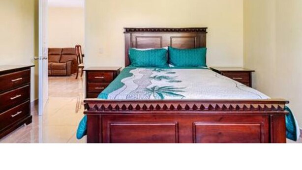 Une chambre à coucher avec un lit en bois, une table de chevet, une commode et une chaise.
