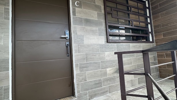 Una habitación moderna con un gran ventanal, una ventana de diseño tipo cuadrícula y una mesa con estructura metálica.