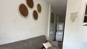 Una sala de estar moderna con un sofá gris, dos tapices tejidos decorativos y un tapiz de macramé.