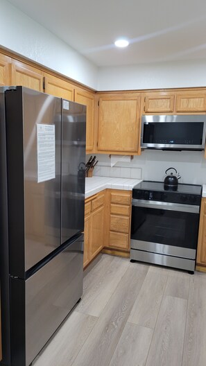 A kitchen with wooden cabinets, a stainless steel refrigerator, a microwave, and a stove. - Snowcreek Resort Vacation Rental 629 (Mammoth Lakes)