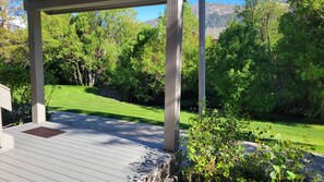A covered outdoor area with a paved deck, surrounded by lush greenery and a grassy lawn. - Snowcreek Resort Vacation Rental 629 (Mammoth Lakes)