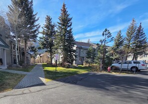 A residential street with houses, trees, and a white SUV parked on the side. - Snowcreek Resort Vacation Rental 629 (Mammoth Lakes)