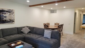 A living room with a gray sectional sofa, a dining table with chairs, and a painting on the wall. - Snowcreek Resort Vacation Rental 629 (Mammoth Lakes)