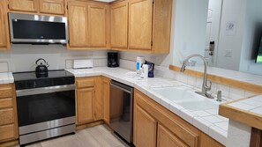 A modern kitchen with wooden cabinets, stainless steel appliances, and a white countertop. - Snowcreek Resort Vacation Rental 629 (Mammoth Lakes)