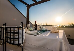 Área de refeições ao ar livre com uma mesa posta para dois, com vista panorâmica.