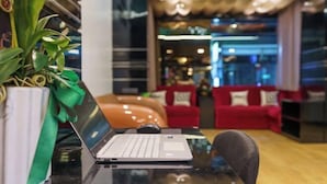 A laptop on a glass table with a potted plant beside it. - Deco Lux Hotel (Bangkok)