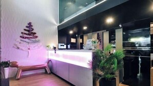 A modern reception area with a wooden bench, a reception desk, and a Christmas tree decoration. - Deco Lux Hotel (Bangkok)