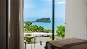 A room with a large window overlooking a coastal view, including a small island and the sea. - Villa Zest 5 bedroom Villa • Rooftop Infinity Pool & Ocean Views (Quepos)