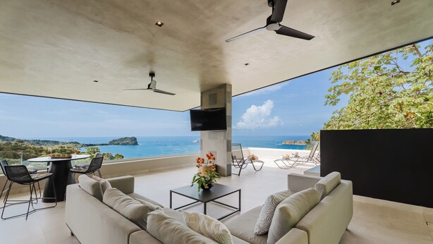 A modern outdoor living area with a sofa, chairs, a table, and a TV. - Villa Zest 5 bedroom Villa • Rooftop Infinity Pool & Ocean Views (Quepos)