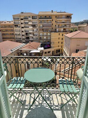 A balcony with a round table and chairs, overlooking a residential area with multi-story buildings. - Duplex in the heart of Menton (Menton)