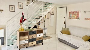 Ein modernes Wohnzimmer mit Treppe, Sofa und einer Kommode mit Schubladen.