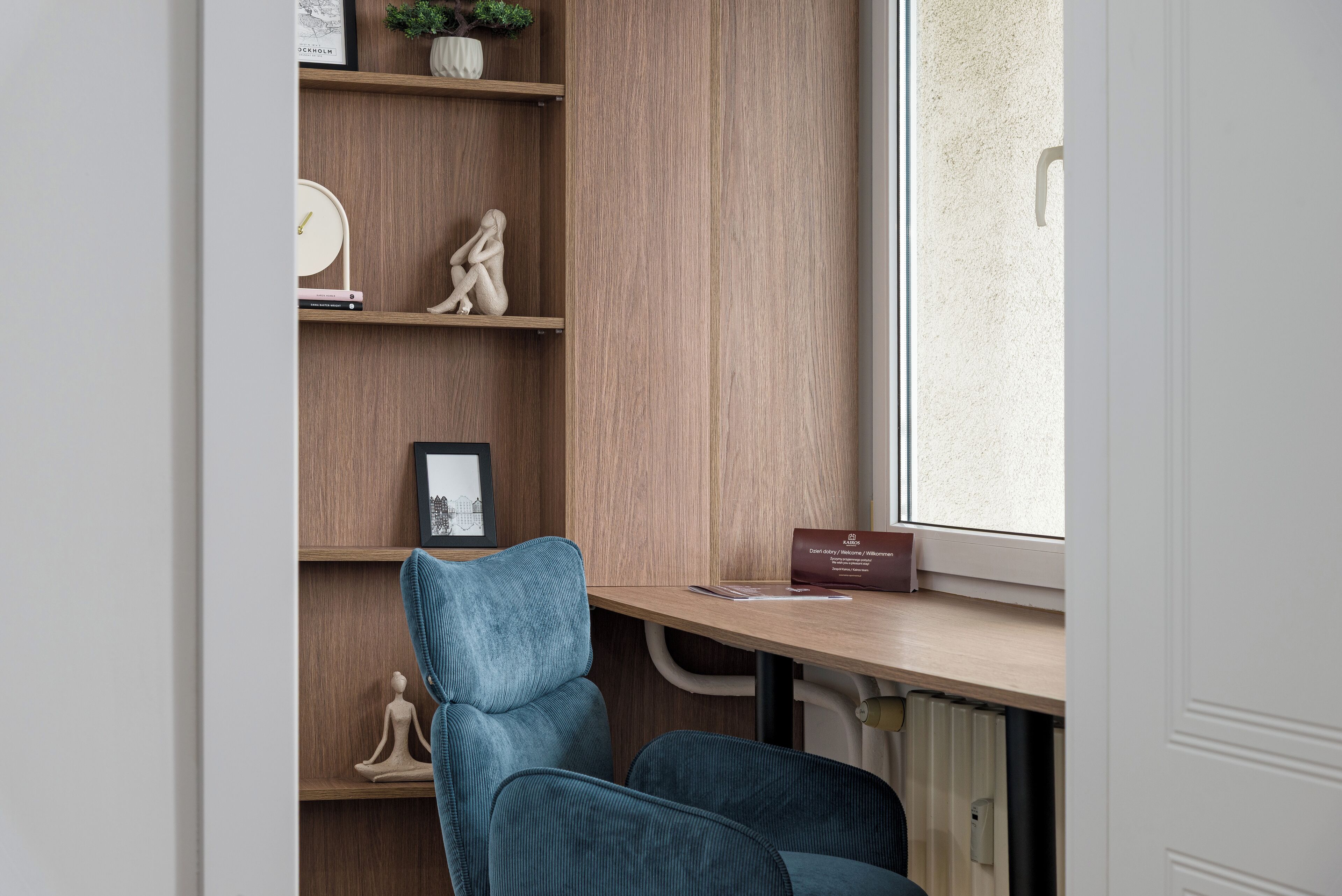 A room with a wooden desk, a chair, a radiator, and a window.