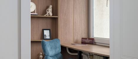 A room with a wooden desk, a chair, a radiator, and a window.