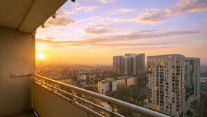 Un balcón con vista a la ciudad al atardecer, mostrando rascacielos y un cielo despejado.