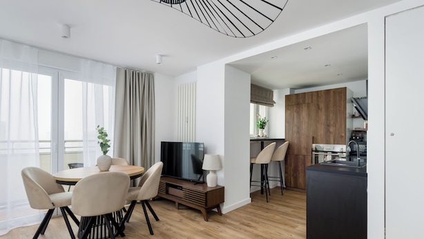 Una sala de estar moderna con comedor, televisor y cocina.