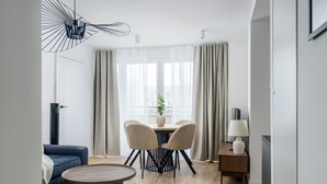 Una sala de estar moderna con un sofá, una mesa de centro redonda y un comedor con una mesa y sillas.
